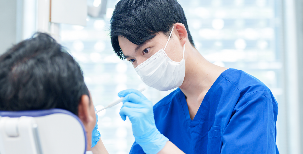 歯科医師が治療中に患者の口腔を診察している様子