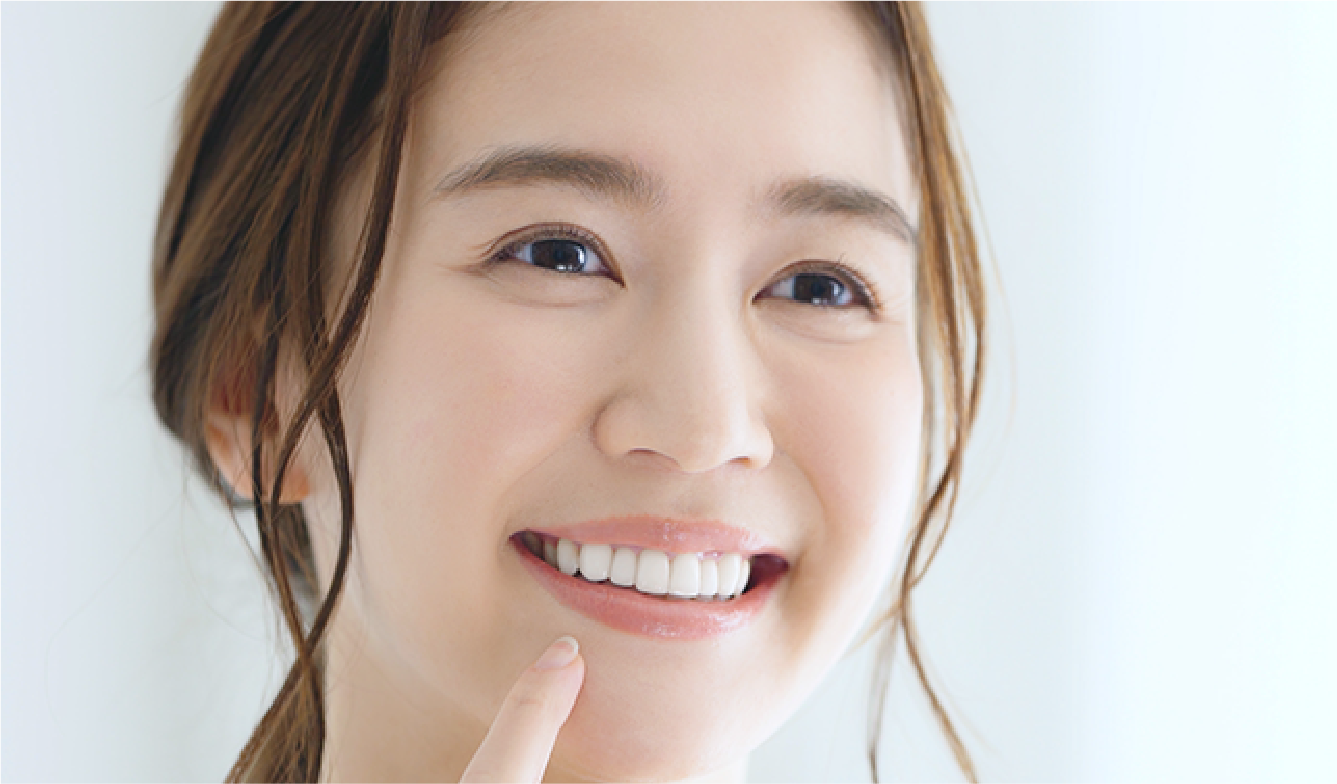 笑顔で口元を指差す女性の写真（白い歯のイメージ）